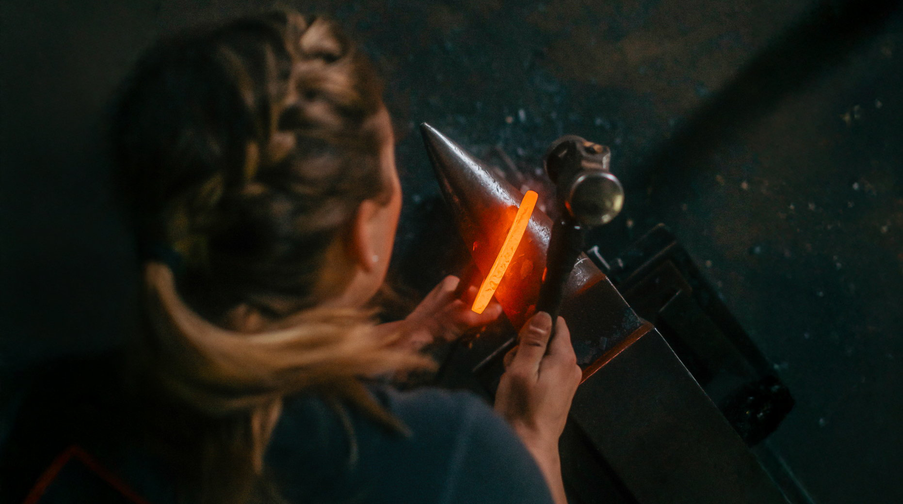 Kvinna håller i hammare och glödande hästsko