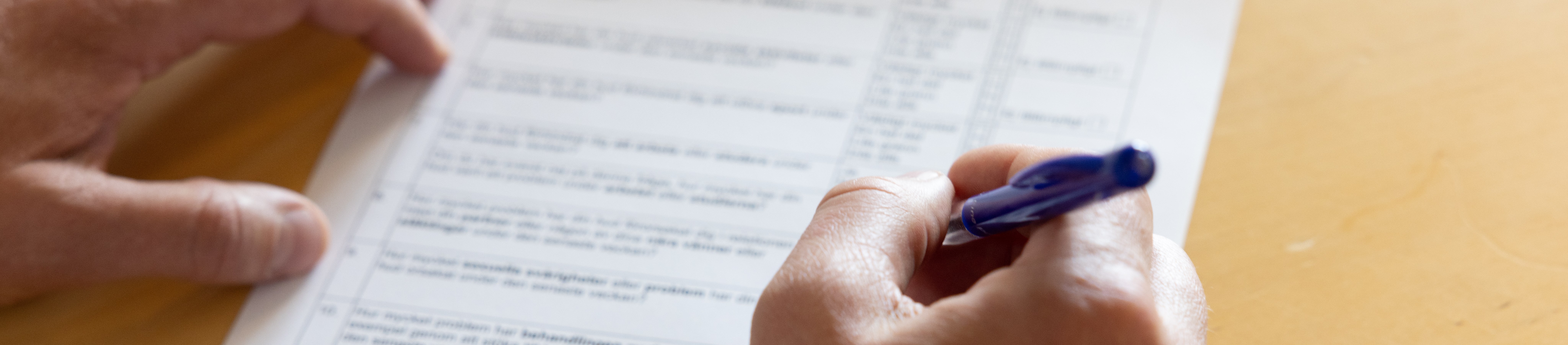 Hand som håller i en penna mot ett papper