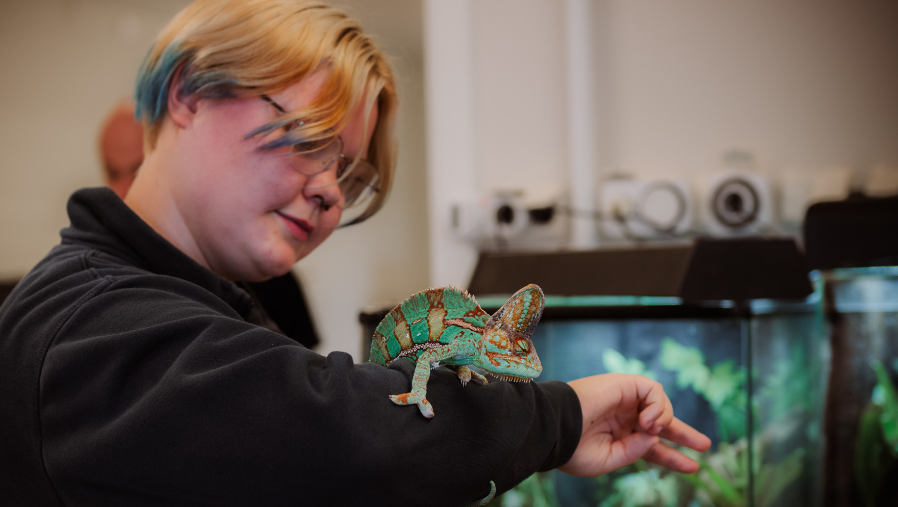 Elev håller grön reptil på armen