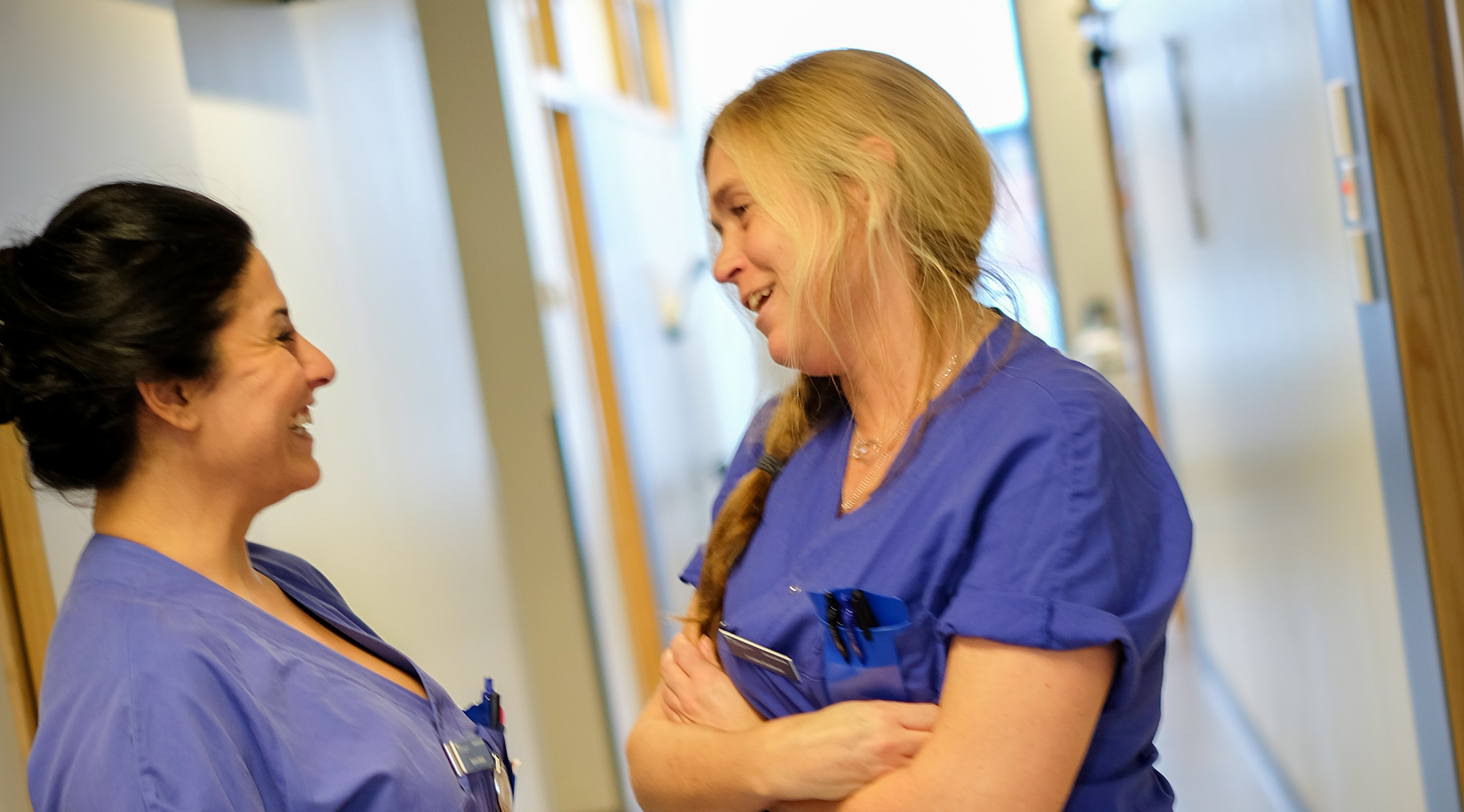 Två medarbetare står i en korridor och pratar med varandra