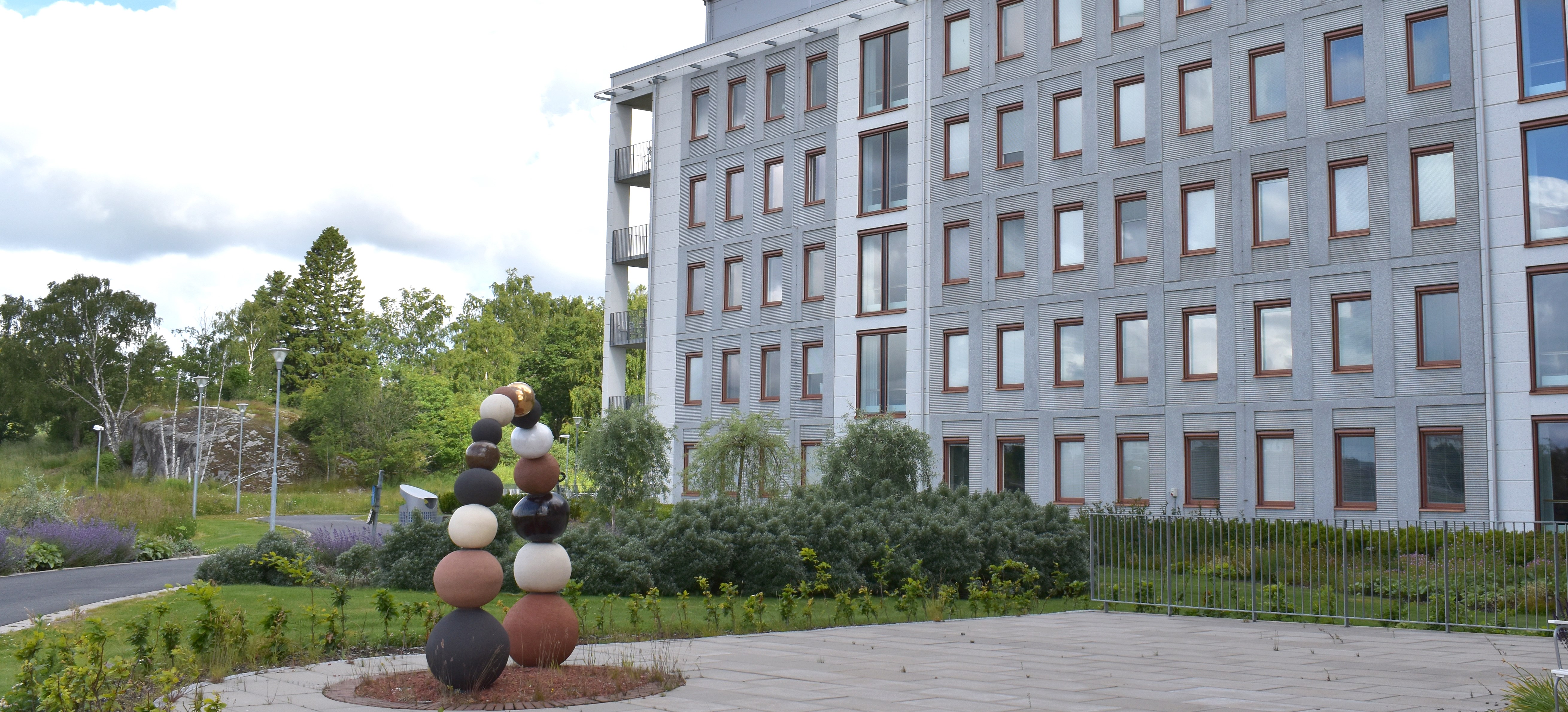 Fasad på vårdbyggnaden. Framför den står ett konstverk.
