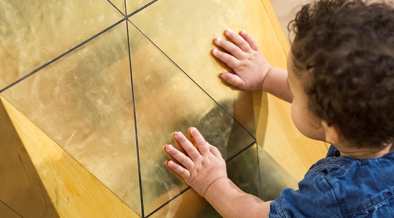 Liten pojke lägger händer mot konstverk