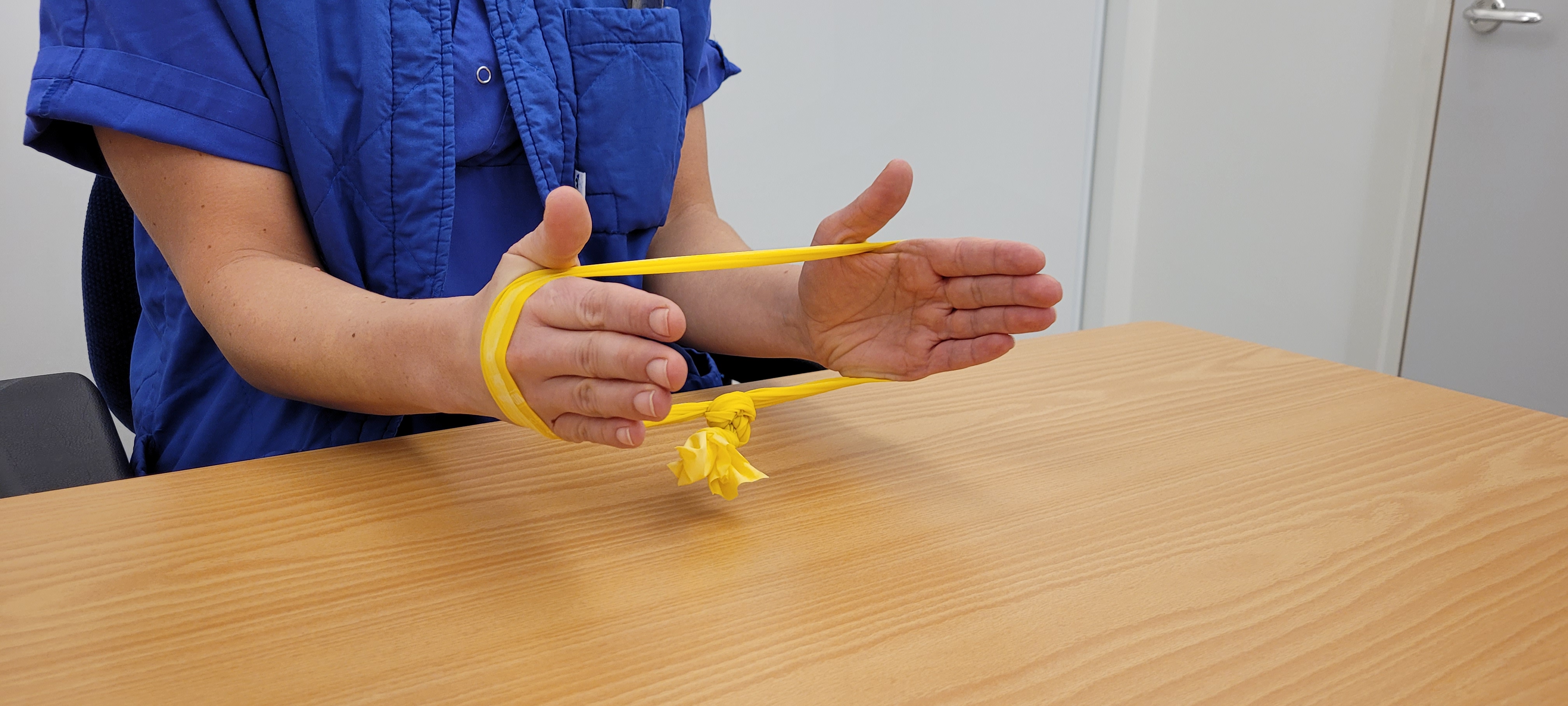 Arbetsterapeut håller i gult gummiband runt händerna