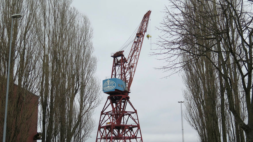 Kran 43 snett bakifrån sett från vägkanten med träd i förgrunden