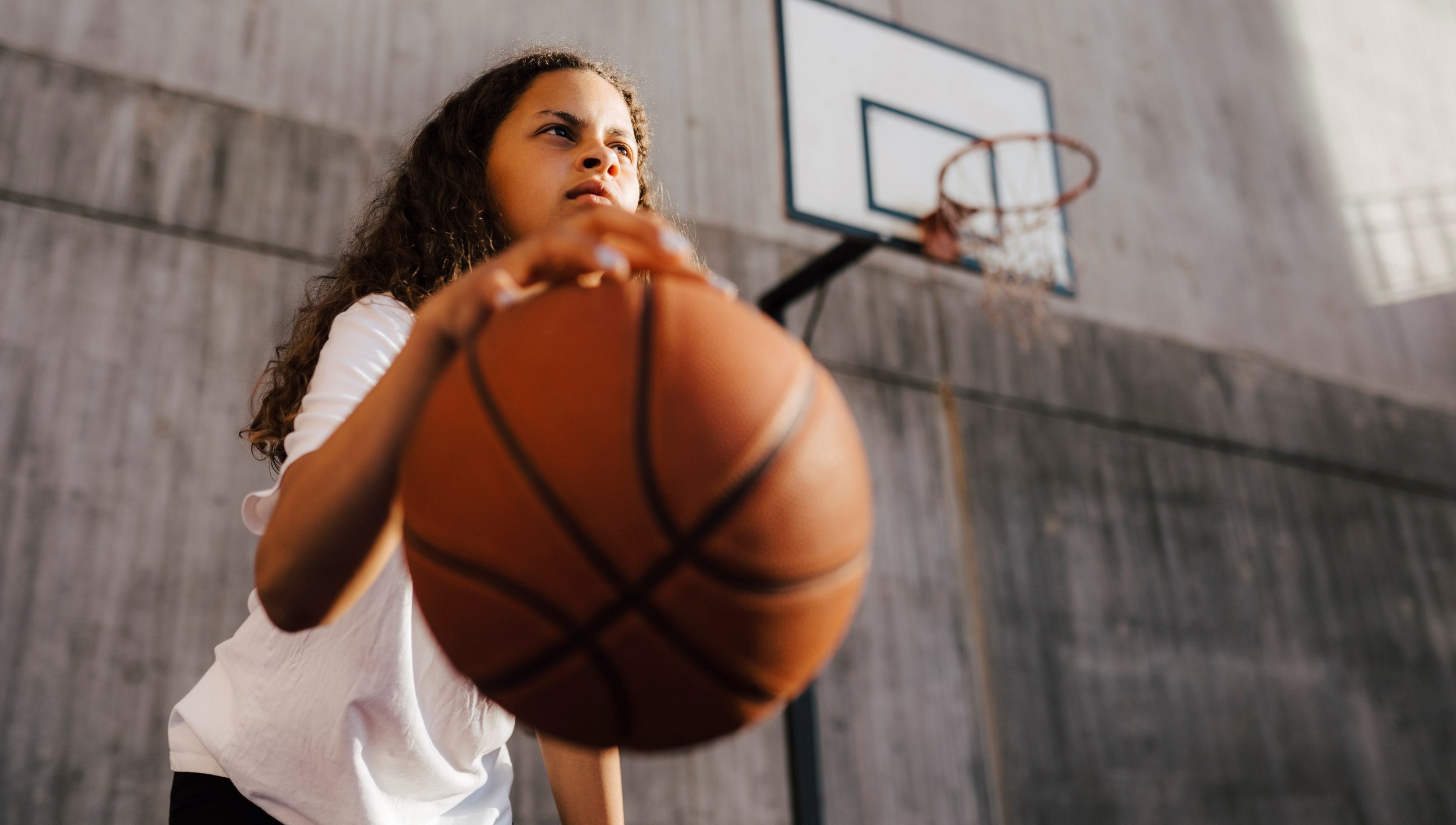 Berson med en basketboll under en basketkorg.
