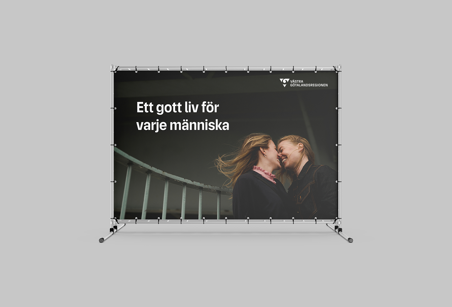 Stor vepa med bild på två leende kvinnor med ansiktena mot varandra. De ser förälskade ut. På bilden finns budskapet Ett gott liv för varje människa och VGR:s logotyp längst upp i högra hörnet